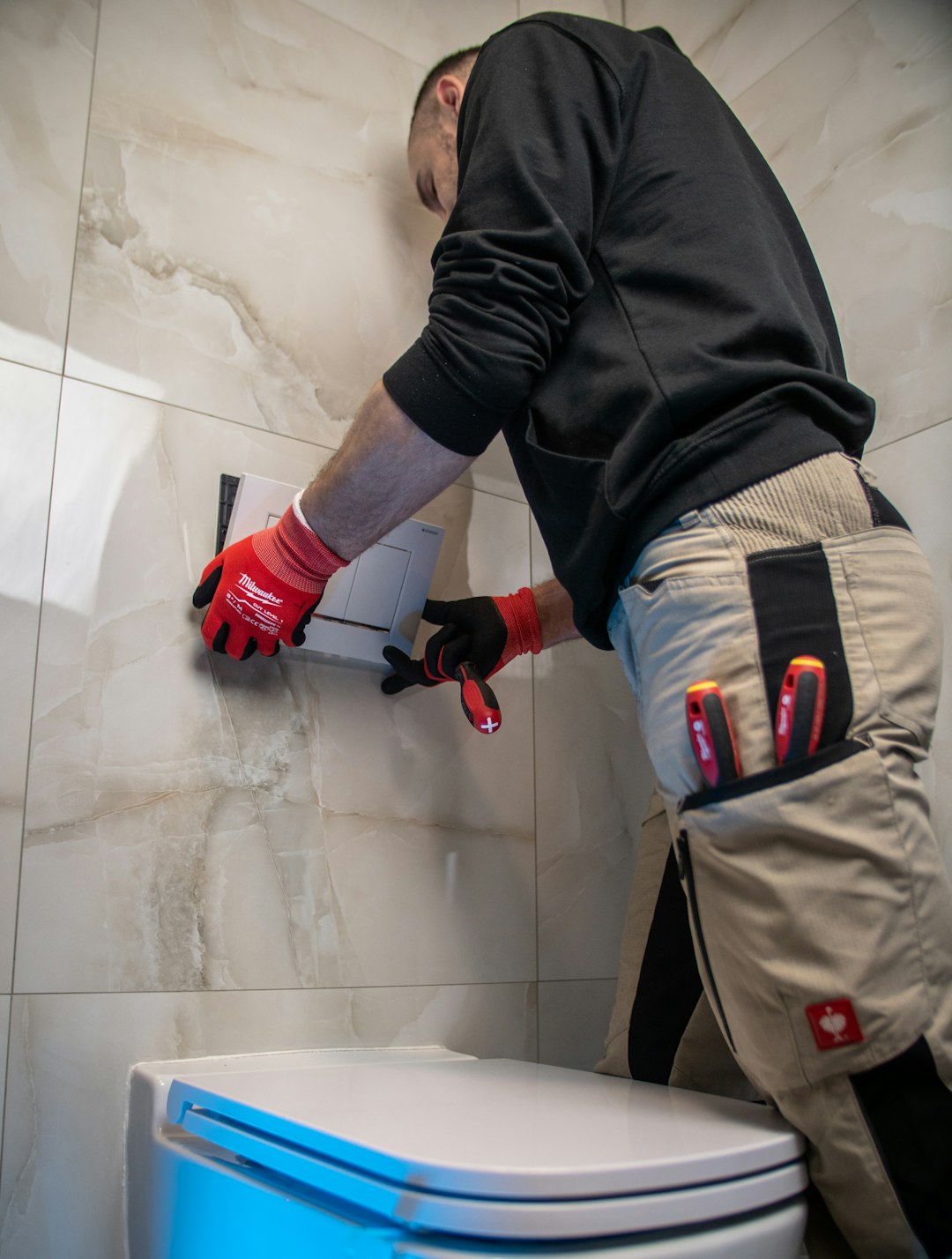 Services a-man-in-a-black-shirt-and-red-gloves-working-on-a-toilet-vagbjhkxg6i